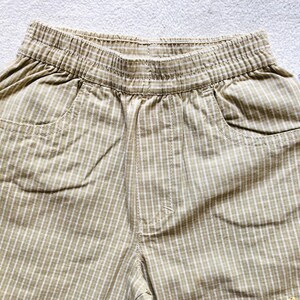 K&ouml;nnte beinhalten: Beige und wei&szlig;e karierte Shorts mit Bund und zwei Taschen.