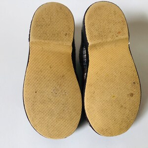May include: A pair of black and white checked slip-on shoes with brown rubber soles. The soles have a textured pattern.