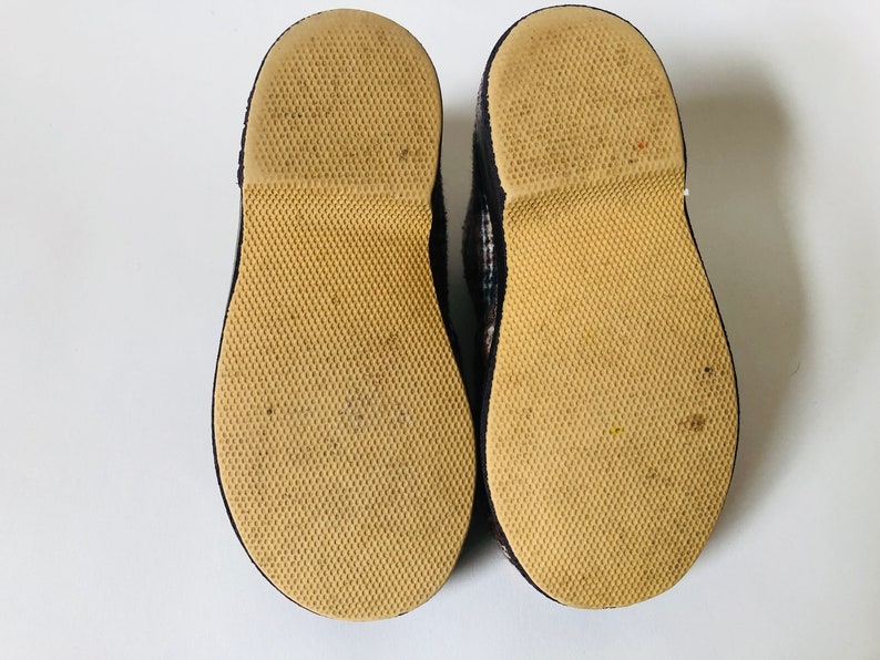 May include: A pair of black and white checked slip-on shoes with brown rubber soles. The soles have a textured pattern.