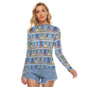 May include: A long-sleeved top featuring a repeating pattern of bell-shaped objects in various colors against a blue background. The top has a crew neck and a fitted silhouette. The model is wearing denim shorts.