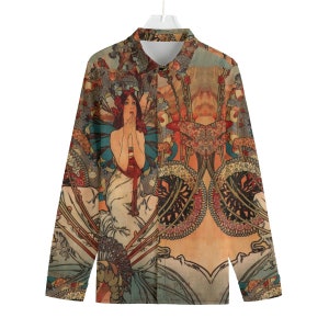 Puede incluir: Una camisa de manga larga con botones con un estampado vintage de art nouveau que presenta a una mujer con un vestido fluido rodeada de motivos florales. La camisa tiene un fondo marrón claro con tonos de rojo, azul, verde y amarillo.
