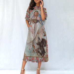 May include: A midi-length dress featuring a Renaissance-style painting print. The dress has short sleeves and a high neckline. The artwork depicts a woman with a halo and an angel. The dress has a floral border at the hem and sleeves.