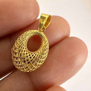 Puede incluir: Un colgante de oro con un diseño de celosía abierta de forma ovalada y una superficie texturizada con tramado cruzado. El colgante incluye una pequeña anilla integrada en la parte superior, marcada con un sello que indica su pureza metálica.