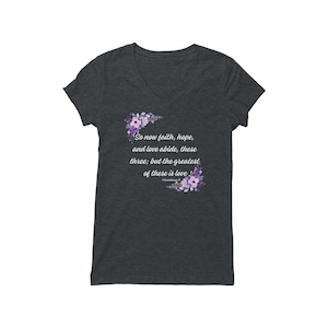 May include: Dark heather grey V-neck t-shirt with a floral design and the text "So now faith, hope, and love abide, these three; but the greatest of these is love."