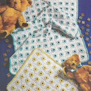 May include: Two crocheted baby blankets with a teddy bear on each. One blanket is white with yellow flowers and the other is white with blue flowers.