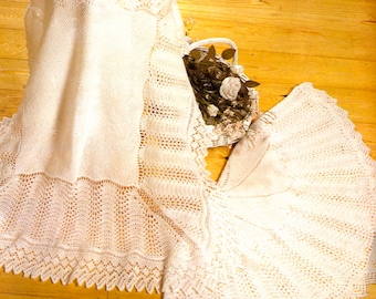 May include: A white crocheted baby blanket with a delicate lace pattern. The blanket is 50 inches by 50 inches.