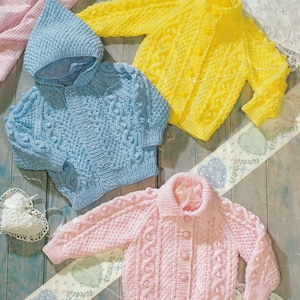 May include: Three knitted baby cardigans in blue, yellow and pink. Each cardigan features a button fastening and a cable knit pattern. The blue cardigan has a hood.
