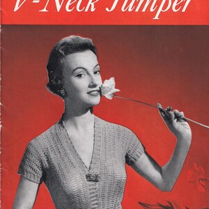 May include: A vintage knitting pattern booklet titled Golden Bell Crepella V-Neck Jumper No. 215. The cover features a red background with a graphic illustration of a short-sleeved, ribbed V-neck sweater and the price of 5D printed in white.