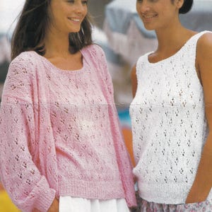 May include: Two women wearing crocheted tops. The woman on the left is wearing a pink top with long sleeves and the woman on the right is wearing a white sleeveless top.