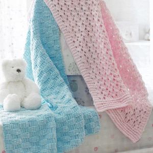 Puede incluir: Dos mantas de bebé de punto, una en azul claro y otra en rosa. La manta azul tiene un patrón tejido y la manta rosa tiene un patrón de encaje.