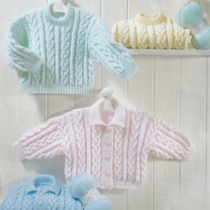 May include: Three baby sweaters in different colors: light blue, pink, and yellow. Each sweater has a cable knit pattern and is displayed on a white shelf with balls of yarn.
