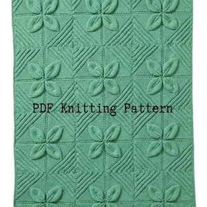 May include: A mint green knitted blanket featuring a repeating square grid pattern with raised leaf motifs in each section. The text "PDF Knitting Pattern" is printed in black across the centre of the fabric, which displays a textured design.