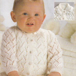 以下が含まれることがあります： ボタン留めのレース襟付きの白いベビー用クロシェカーディガン。カーディガンは繊細な透かし模様になっています。