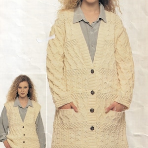 May include: Cream-coloured, long-sleeved cardigan with a cable knit design. The sweater has a V-neck, large pockets, and dark brown buttons. A matching cream-coloured vest with buttons is also shown.