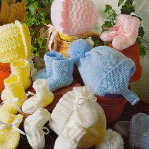 May include: A set of knitted baby clothes in pink, blue, and white. The set includes a hat, booties, and a sweater. The clothes are made with a soft, delicate yarn.