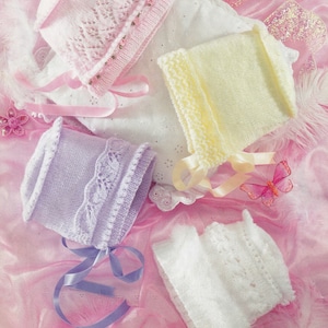 May include: Four knitted baby hats in different colors: pink, yellow, lavender, and white. Each hat has a delicate lace pattern and a satin ribbon tied around it.
