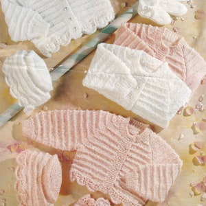 May include: Three knitted baby sets, one white and two pink, with matching hats and booties. The sets feature a cardigan with a button closure and a scalloped edge.