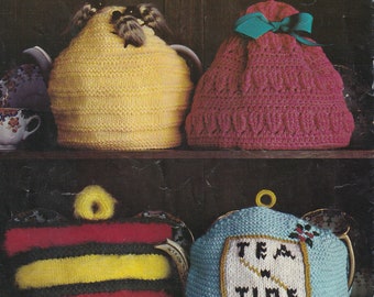 May include: Four knitted teapot cosies in different colours and designs. The first is yellow with bees, the second is pink with a bow, the third is black, yellow, and red striped, and the fourth is blue with the words "Tea Time" embroidered on it.