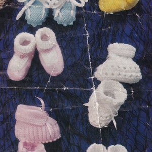 May include: A collection of knitted baby booties in various colors, including pink, blue, and yellow. The booties are made with a soft, textured yarn and feature different styles, such as lace and ribbon accents.