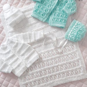 May include: A white knitted baby blanket with a delicate lace pattern, a white knitted baby sweater, and a white knitted baby hat.  There is also a light blue knitted baby cardigan and a light blue knitted baby hat.