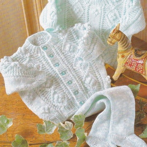 Könnte beinhalten: Ein Set aus zwei hellblauen gestrickten Babysweatern, bestehend aus einer Strickjacke mit Knöpfen und einer passenden Strickhose.