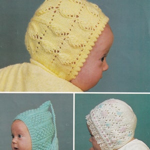 Könnte beinhalten: Eine Sammlung von drei gestrickten Babyhauben. Die gelbe Haube hat ein strukturiertes Blättermuster und einen gewellten Rand. Die blaue Haube hat eine spitze Oberseite mit einer Quaste. Die weiße Haube hat ein Blumenmuster und eine Spitzenborte.