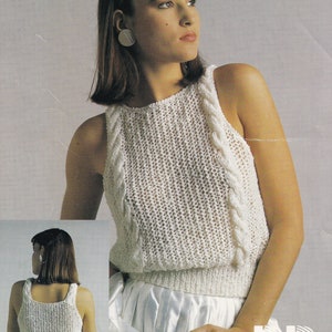 Könnte beinhalten: Ein weißes ärmelloses Stricktop mit Zopfmuster. Das Top hat einen runden Ausschnitt und eine figurbetonte Silhouette.
