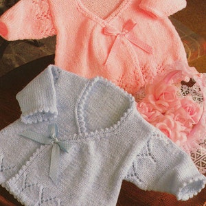 May include: Two knitted baby cardigans, one pink and one light blue, with a lace pattern and a tie at the neckline.
