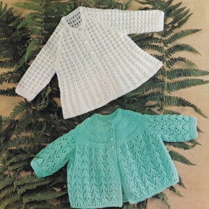 May include: Two knitted baby cardigans, one white and one teal green, with a button closure and lacy stitch pattern.
