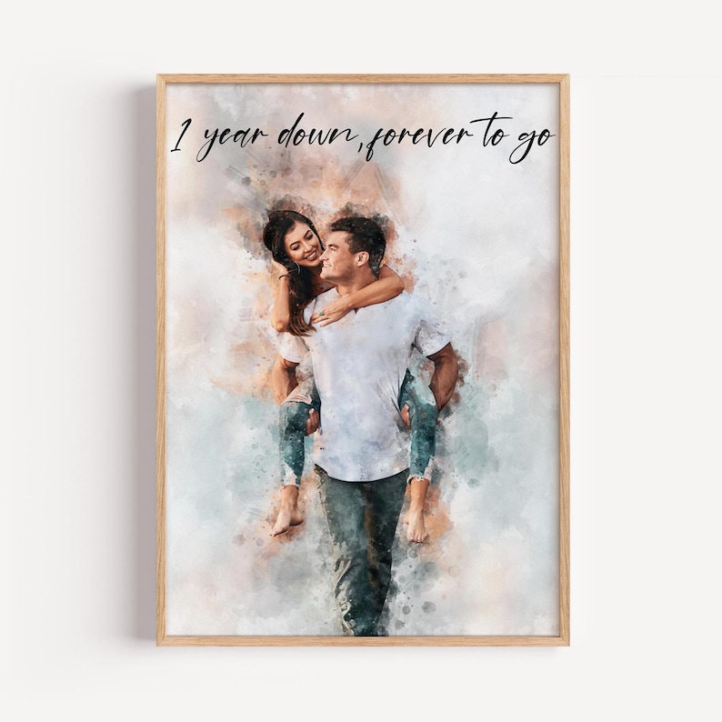 Pu&ograve; includere: Una stampa ad acquerello incorniciata con una coppia, con la donna sulla schiena dell'uomo. La stampa presenta il testo "1 year down, forever to go" in stile scritto a mano. L'opera &egrave; in una cornice di legno.