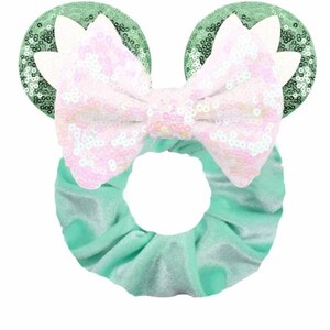 May include: A green velvet scrunchie with a large pink and white sequined bow and green sequined mouse ears.