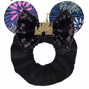 May include: Black sequin bow with a gold glitter castle charm, attached to a black velvet headband with blue and pink firework print ears.