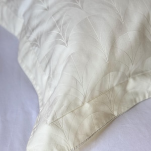 May include: A white pillowcase featuring a subtle, tone-on-tone fan-shaped pattern. The fabric has a smooth, slightly lustrous finish with a stitched border detail along the edge, creating a clean and uniform appearance across the textile surface.