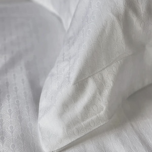 May include: A white pillowcase and matching bed sheet set featuring a repeating tonal fan-shaped pattern. The fabric has a subtle sheen and a textured weave, showcasing a consistent decorative motif across the entire surface of the bedding.