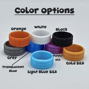 May include: A collection of colorful silicone rings in various shades, including orange, white, black, grey, translucent blue, light blue silk, purple silk, and gold silk. The text "Color options" is displayed above the rings.
