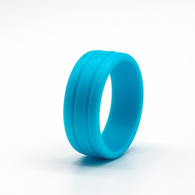 May include: A vibrant, turquoise silicone ring with three parallel grooves. The ring is a solid, seamless band, perfect for everyday wear. The bright blue color stands out against the white background.