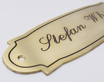 May include: A gold-colored metal nameplate with a black border and the name "Stefan" engraved in cursive script.