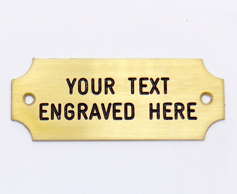 May include: A gold-colored metal plaque with rounded edges and two holes. The text "YOUR TEXT ENGRAVED HERE" is engraved on the plaque.