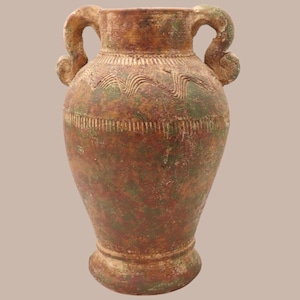 May include: A large, antique-style vase with two ornate handles. The vase features a textured, aged appearance with a blend of brown, green, and gold tones. Decorative bands and patterns encircle the vessel, adding to its vintage aesthetic.