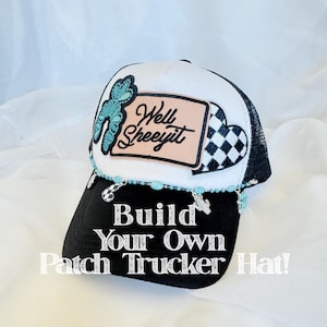 Puede incluir: Gorra de camionero en blanco y negro con la parte trasera de malla. La gorra presenta un parche con las palabras "Well Sheeeyit" y un diseño de trébol turquesa. La visera tiene el texto "Build Your Own Patch Trucker Hat!" y está decorada con cuentas turquesas.