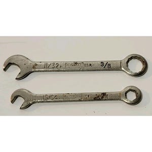 May include: Two vintage metal wrenches. The top wrench is marked "11/32" and "3/8". The bottom wrench is marked "15/64" and "1/4". Both wrenches are stamped "U.S.A."
