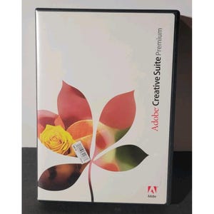 May include: Adobe Creative Suite Premium software box. The cover features a floral design with red, orange, and green hues, and a yellow rose. The Adobe logo is at the bottom right.