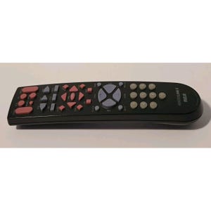 May include: Black RCA Systemlink 4 remote control with pink, gray, and white buttons. The remote has a curved design and features a variety of buttons for controlling a television or other electronic devices.