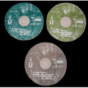 May include: Three PC game discs for Tom Clancy's Splinter Cell. Each disc features a character with night vision goggles and a gun. The discs are numbered 1, 2, and 3, with a green, olive green, and grey color scheme.