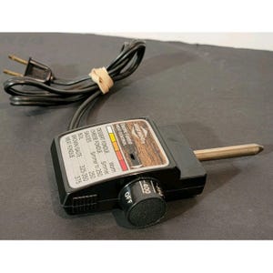 May include: A black West Bend electric fondue heat control with a wooden-look panel. The control has a temperature dial, a probe, and a power cord. The dial has temperature settings from Off to 400 degrees Fahrenheit.
