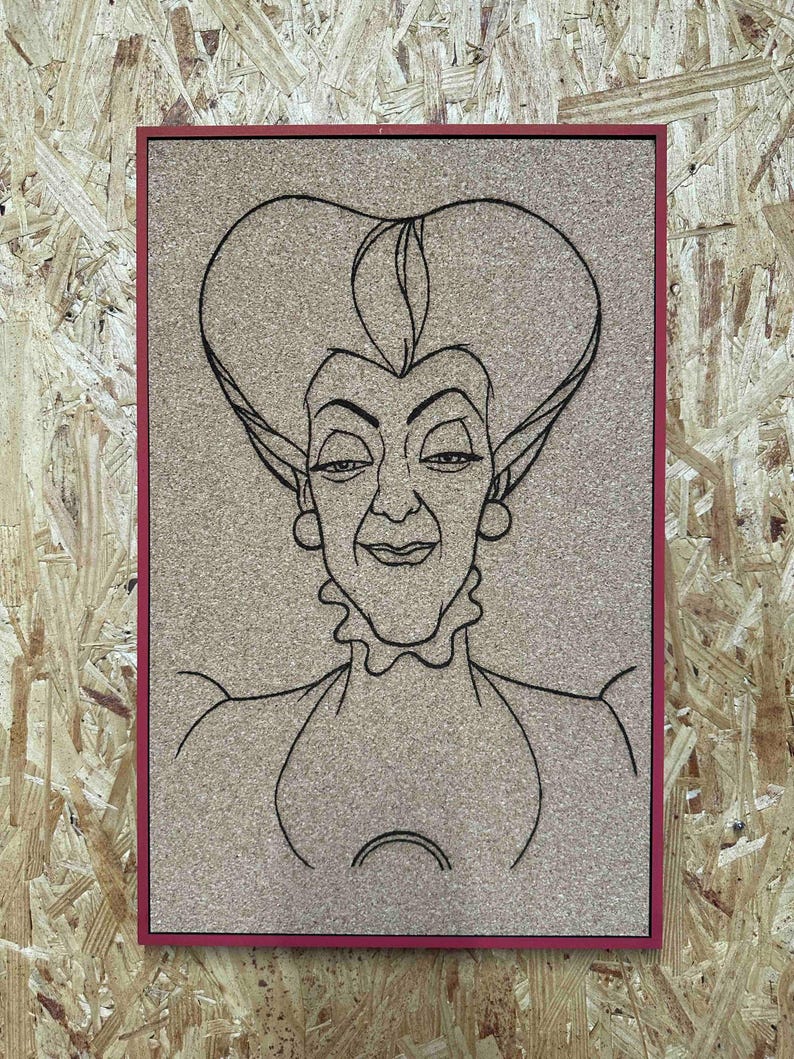 Puede incluir: Un corcho enmarcado con un dibujo lineal negro de una mujer con una expresi&oacute;n severa y un peinado grande. El marco es de color rojo oscuro. El fondo es un corcho marr&oacute;n claro.