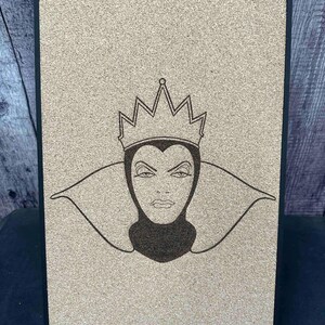 Puede incluir: Un tablero rectangular de corcho con marco negro, grabado con l&aacute;ser con la imagen de una reina severa con corona y cuello alto. La obra de arte es de color marr&oacute;n oscuro sobre corcho marr&oacute;n claro. El tablero est&aacute; sostenido por un peque&ntilde;o soporte met&aacute;lico.