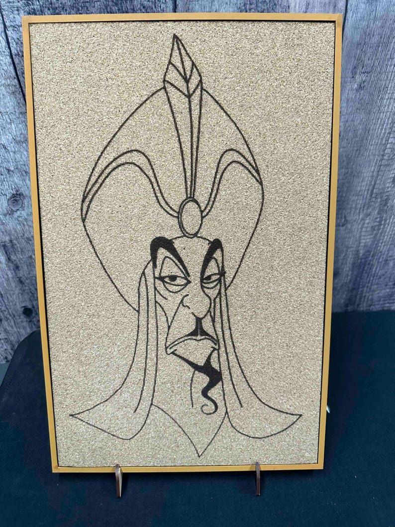 Puede incluir: Un corcho enmarcado con un dibujo lineal negro de un personaje con un tocado alto y una barba larga y puntiaguda. El marco es de color marr&oacute;n claro y el fondo es de color beige claro.