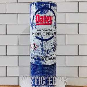 May include: A cylindrical can of Oatey Purple Primer for CPVC and PVC pipes. The can is primarily blue and white with the Oatey logo in red. The text "PURPLE PRIMER" is prominently displayed. The bottom of the can has a clear acrylic base with the text "RUSTIC EDGE CUSTOMS".