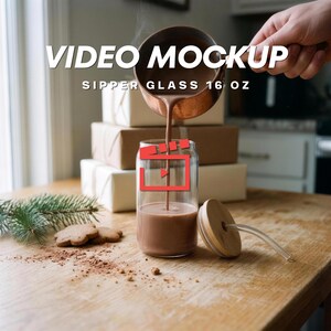 Puede incluir: Un vaso transparente de 16 oz con tapa de bambú y pajita transparente. Una jarra de color cobre vierte un líquido marrón en el vaso. El texto VIDEO MOCKUP SIPPER GLASS 16 OZ es visible. Un icono de reproducción rojo está centrado.